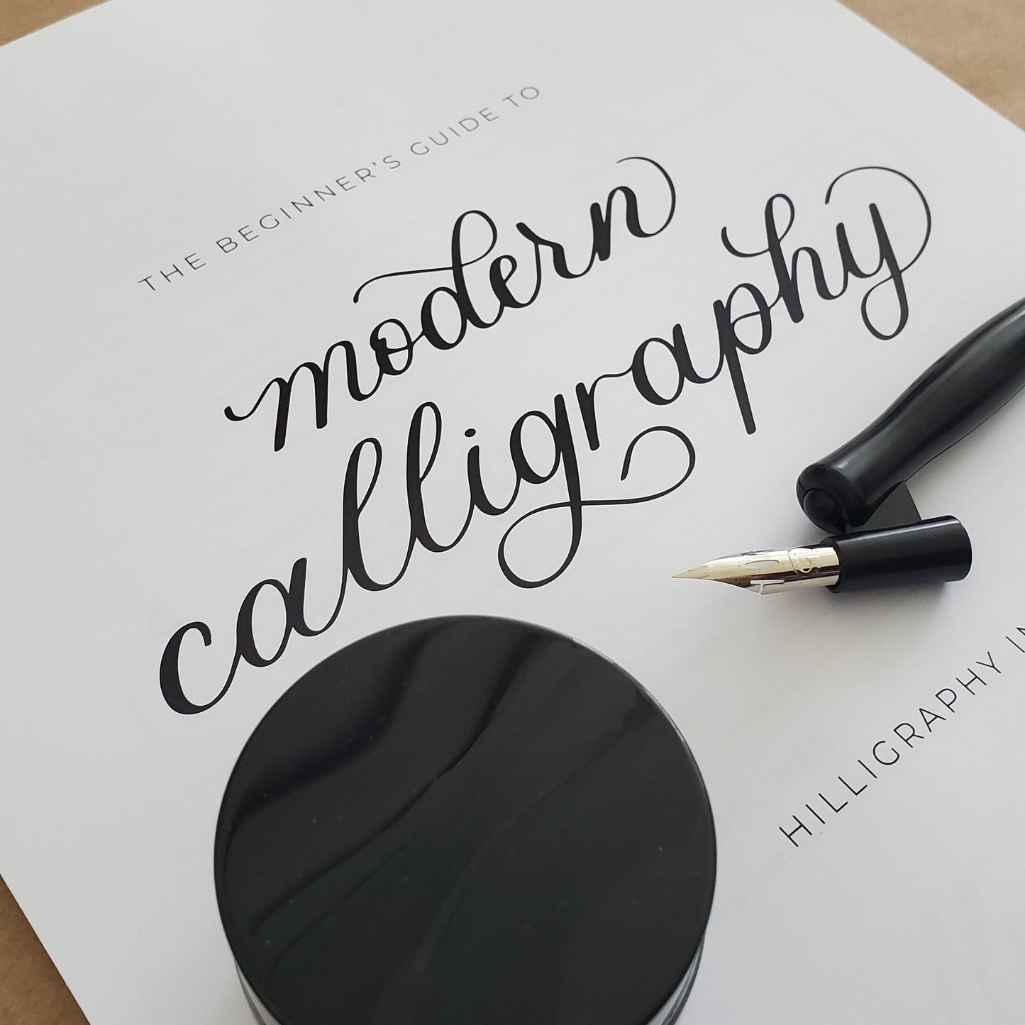 Black ink pad and calligraphy pen on a white paper with text