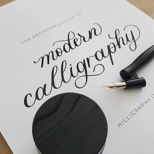 Black ink pad and calligraphy pen on a white paper with text