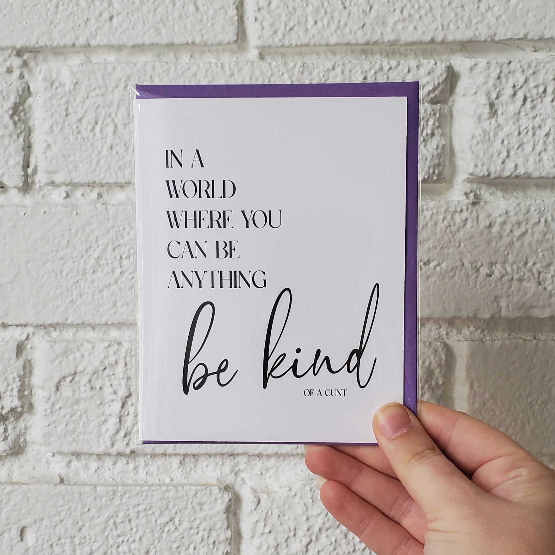 Hand holding a card with text against a textured white wall