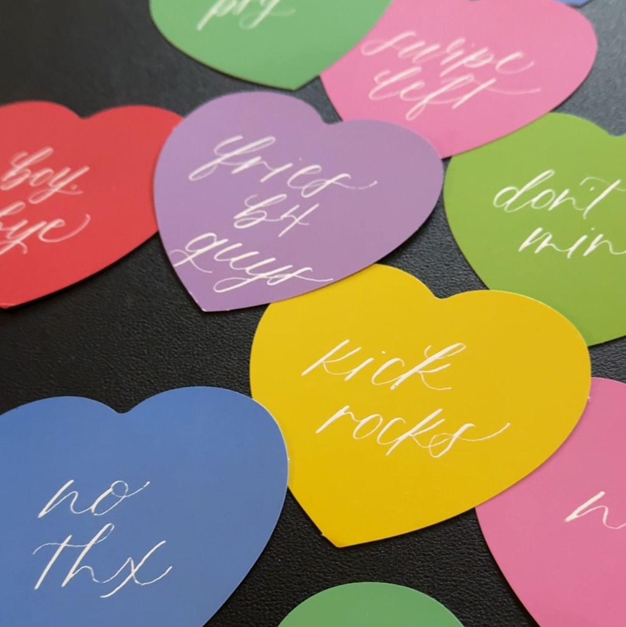 Colorful heart-shaped paper with various phrases on a black surface